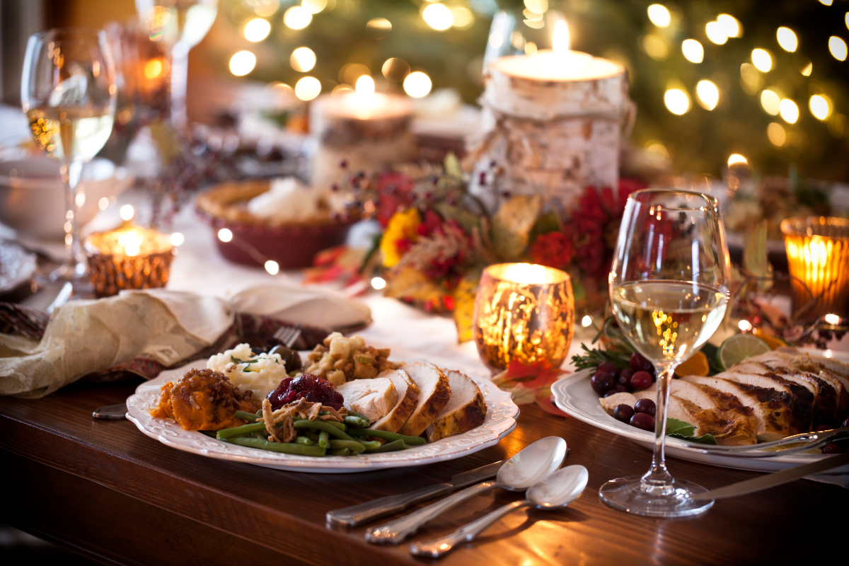 A table set for a christmas dinner with plates of food and wine glasses