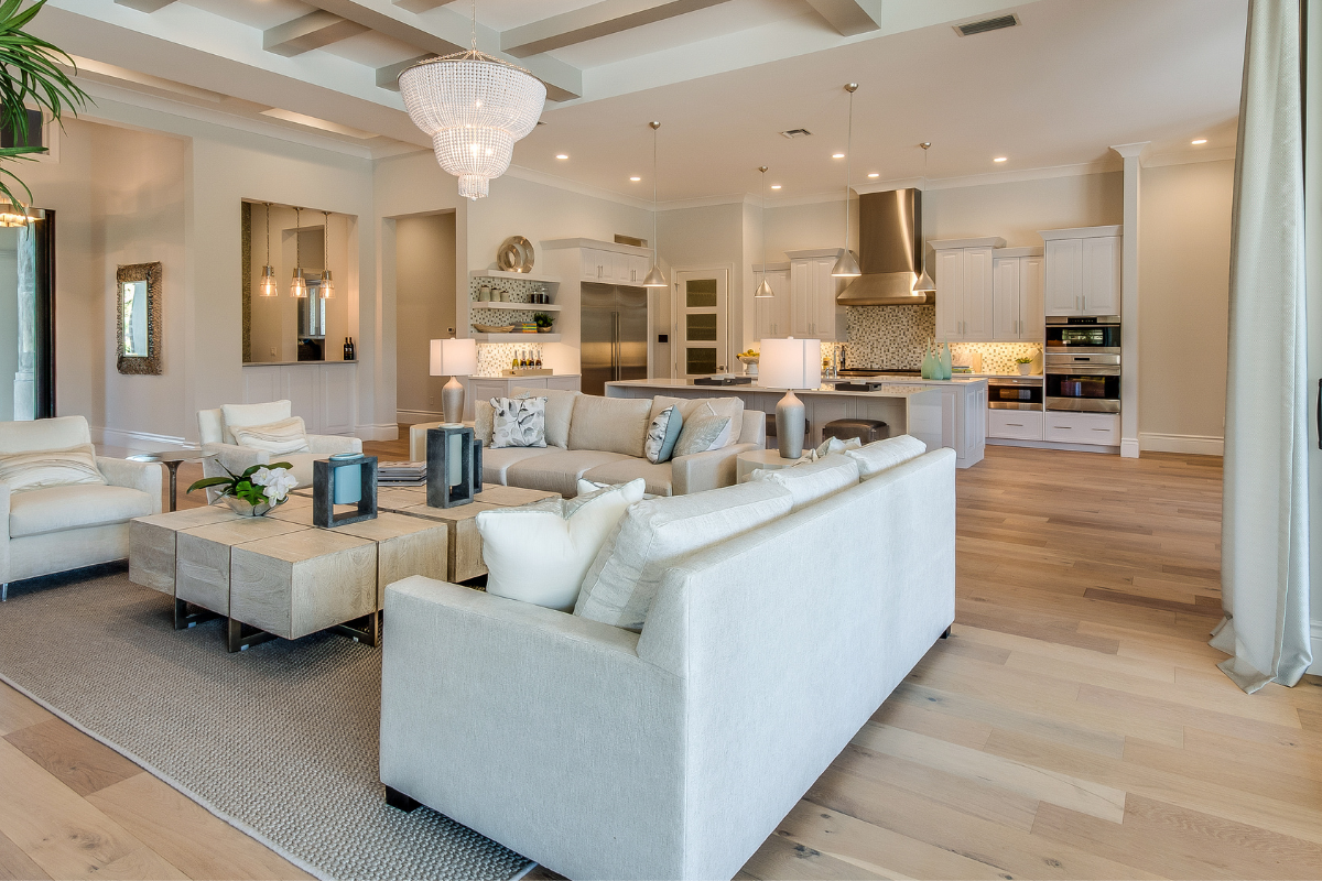 A living room with white furniture and a chandelier hanging from the ceiling