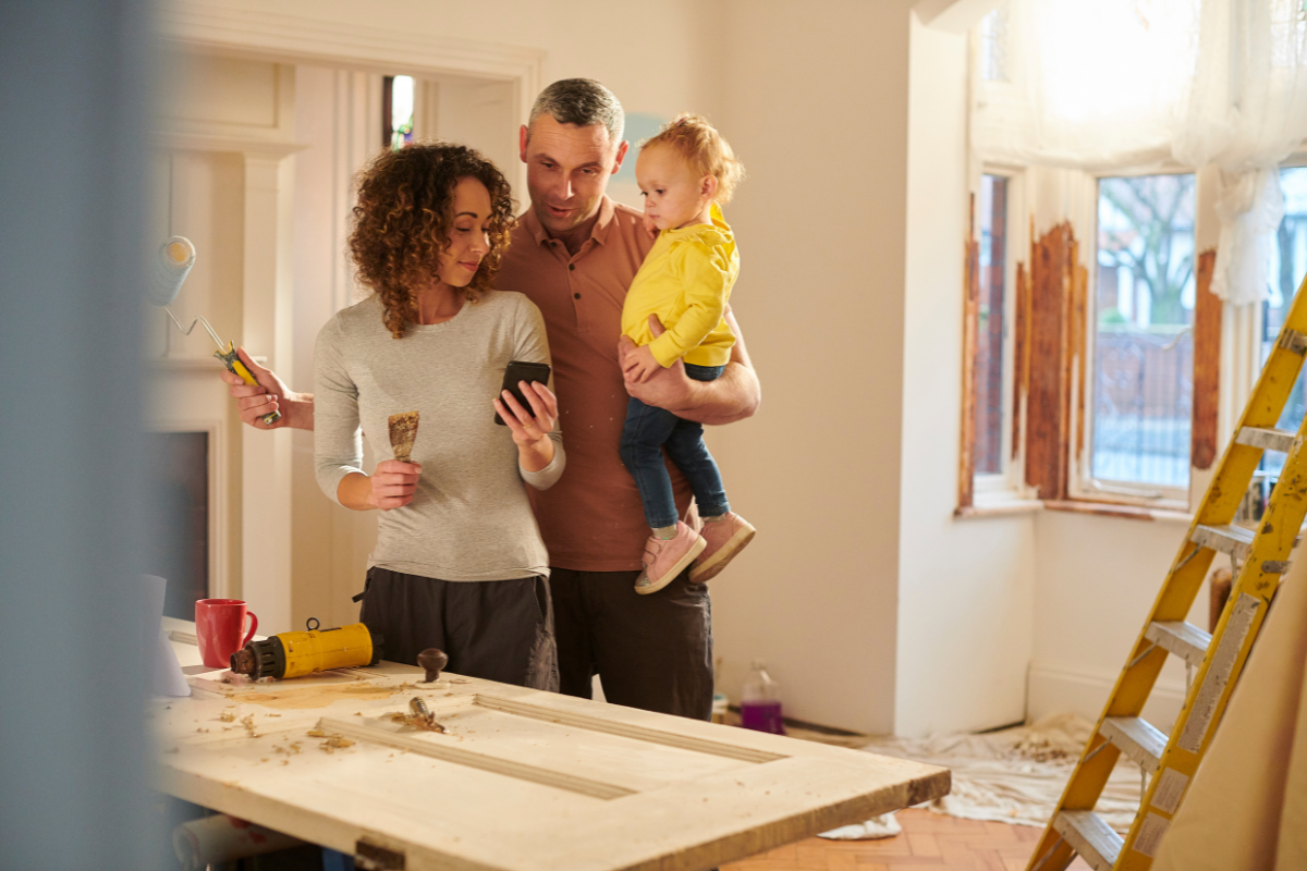 A man and woman are holding a child while looking at a cell phone.