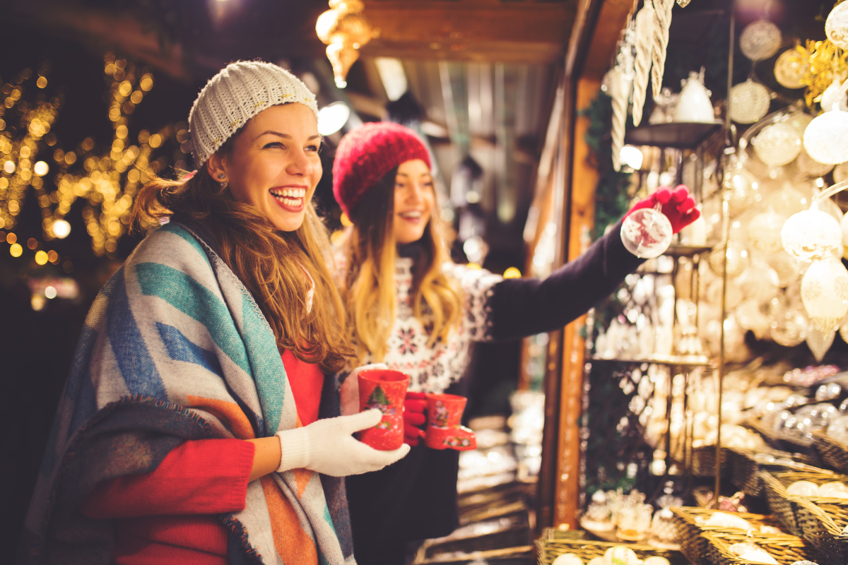Two women are looking at christmas decorations at a market.