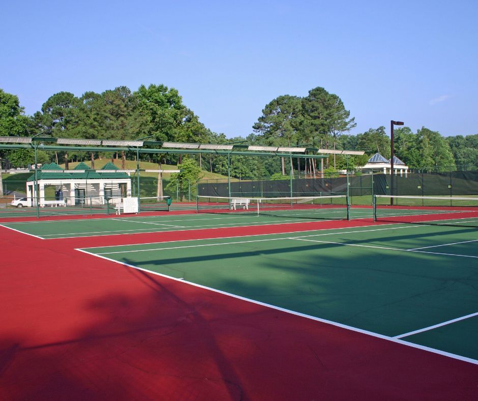 A green and red tennis court with trees in the background