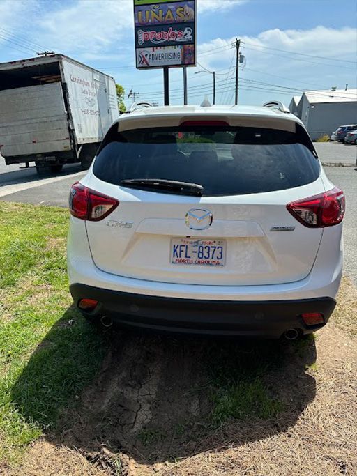 A white car is parked in a grassy area next to a truck.