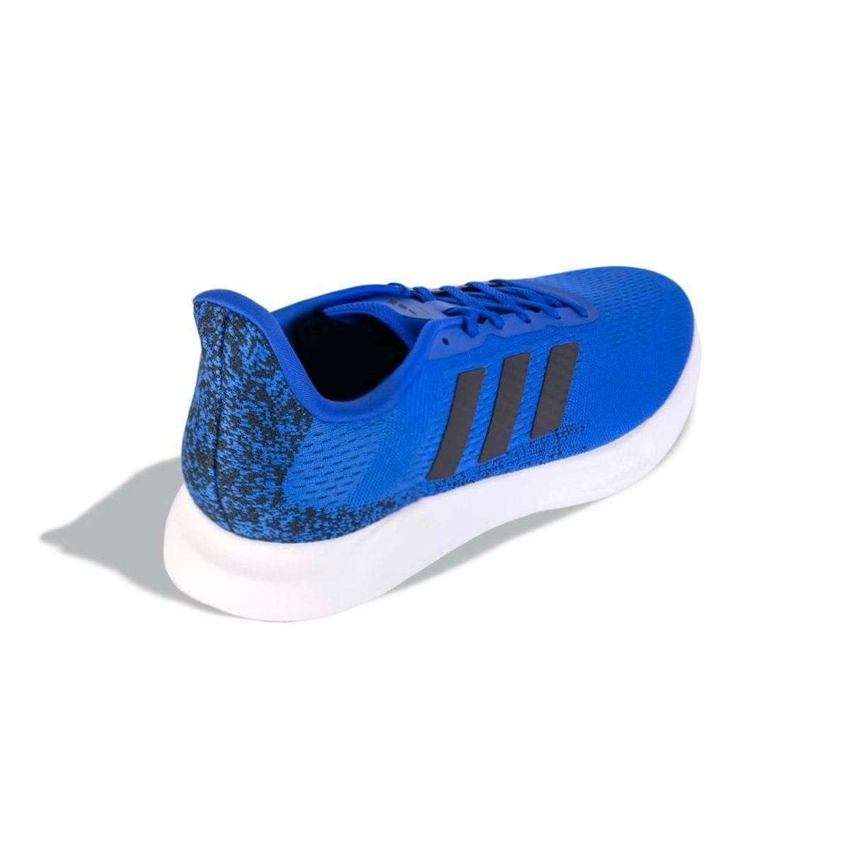 Zapatilla de running Adidas de color azul con rayas negras sobre suela blanca.