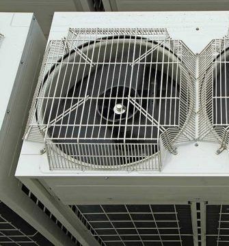 Top-down view of a white industrial HVAC unit with circular fans protected by metal wire grilles.