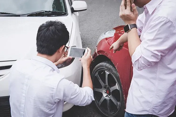Two men are taking a picture of a car accident.