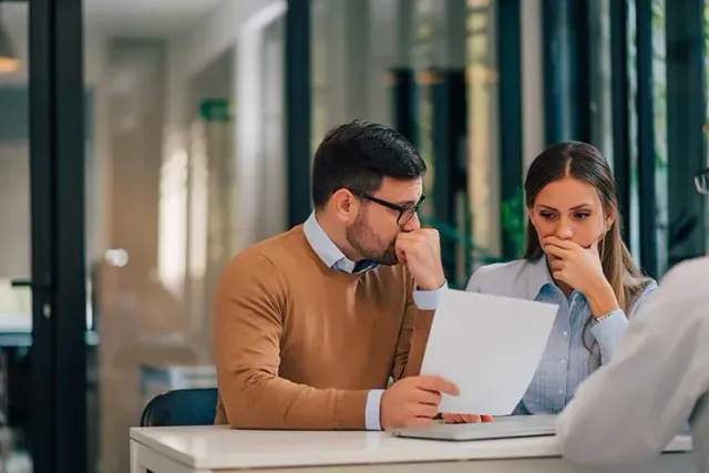 A man and a woman are sitting at a table looking at a piece of paper.