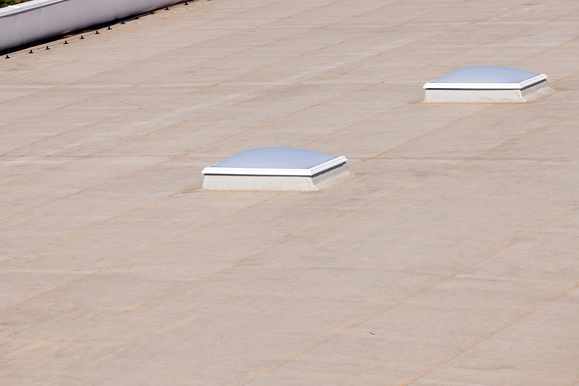 Flat, light-colored commercial roof with two rectangular skylights