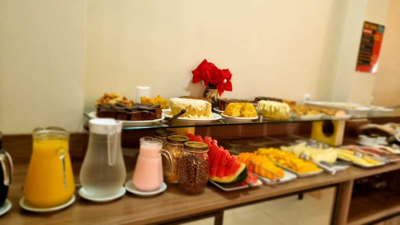Buffet de café da manhã com frutas, bolos, sucos e doces.