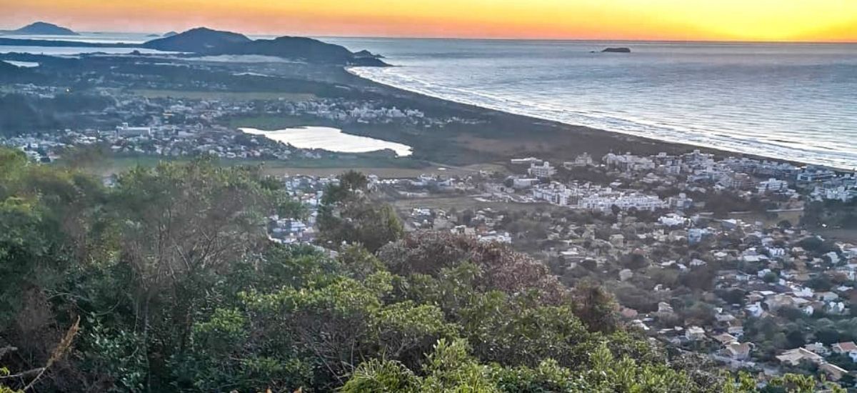 Uma vista de uma cidade a partir de uma colina com vista para o oceano ao pôr do sol.
