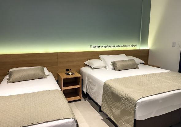 Um quarto de hotel com duas camas e uma mesa de cabeceira