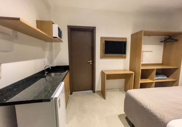 Um quarto de hotel com duas camas, uma cozinha e uma televisão.