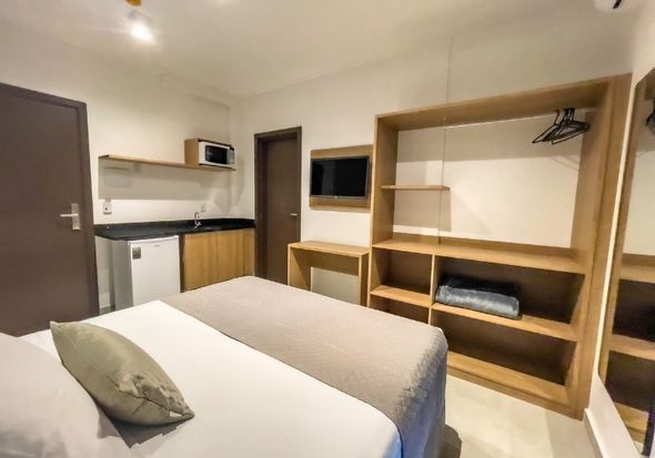 Um quarto de hotel com cama, prateleiras e televisão.