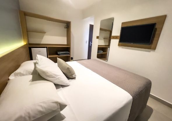 Um quarto de hotel com uma cama grande e uma TV de tela plana na parede.