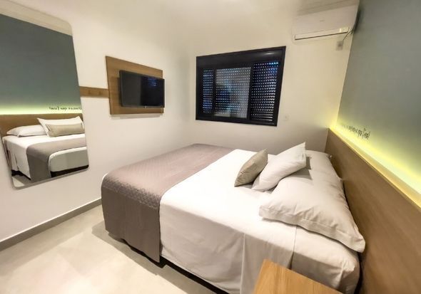 Um quarto de hotel com uma cama e um espelho