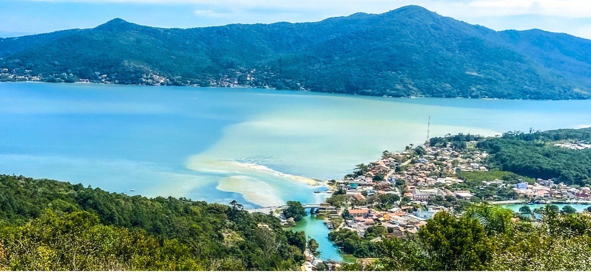 Uma vista aérea de uma pequena cidade no meio de uma grande massa de água cercada por montanhas.