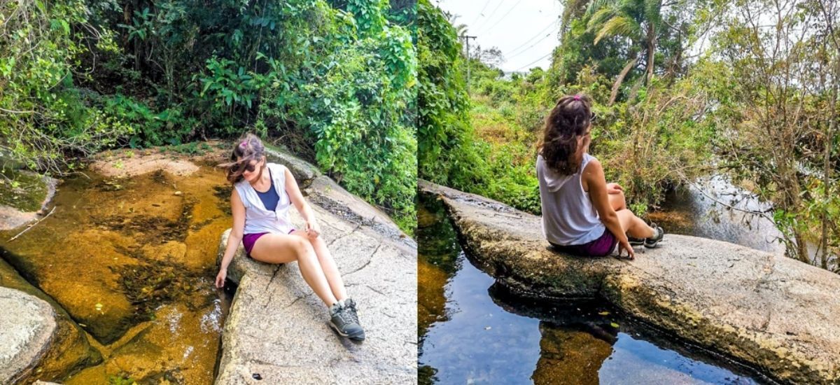 Uma mulher está sentada em uma pedra perto de um rio.