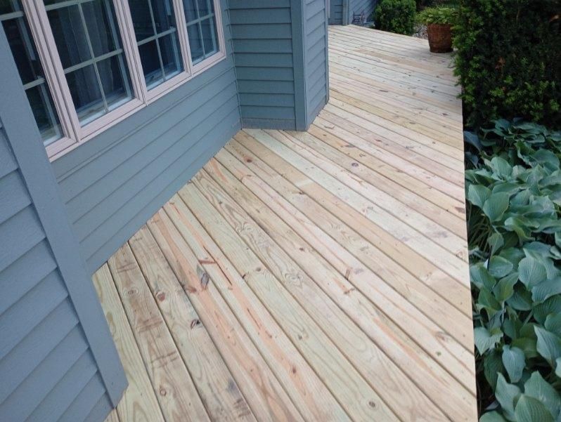 A wooden deck with a window on the side of a house.