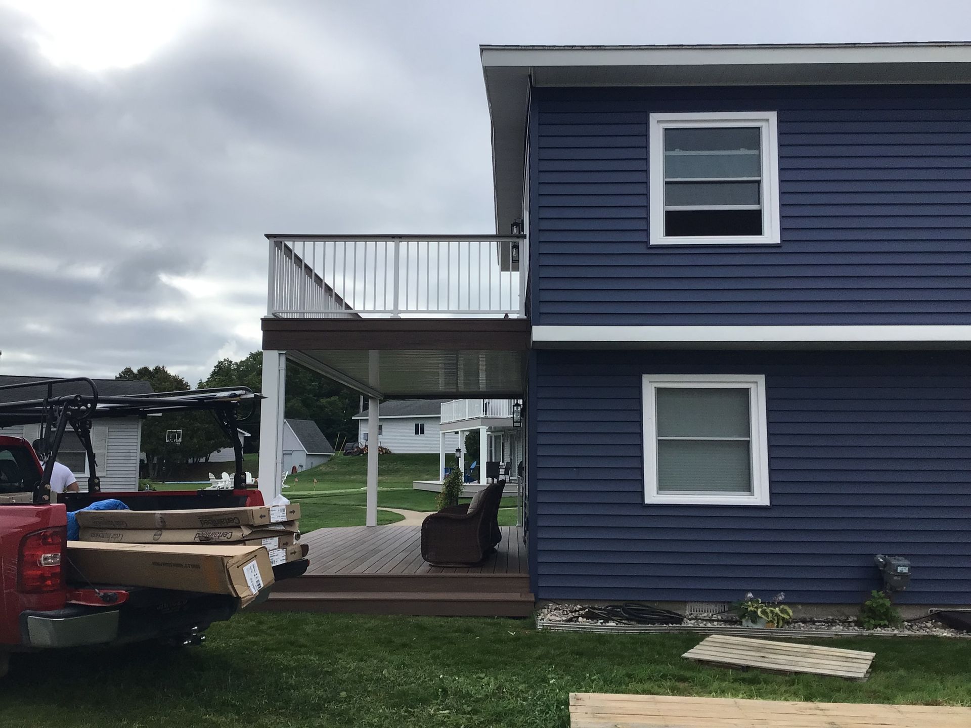 A blue house with a deck and a red truck parked in front of it