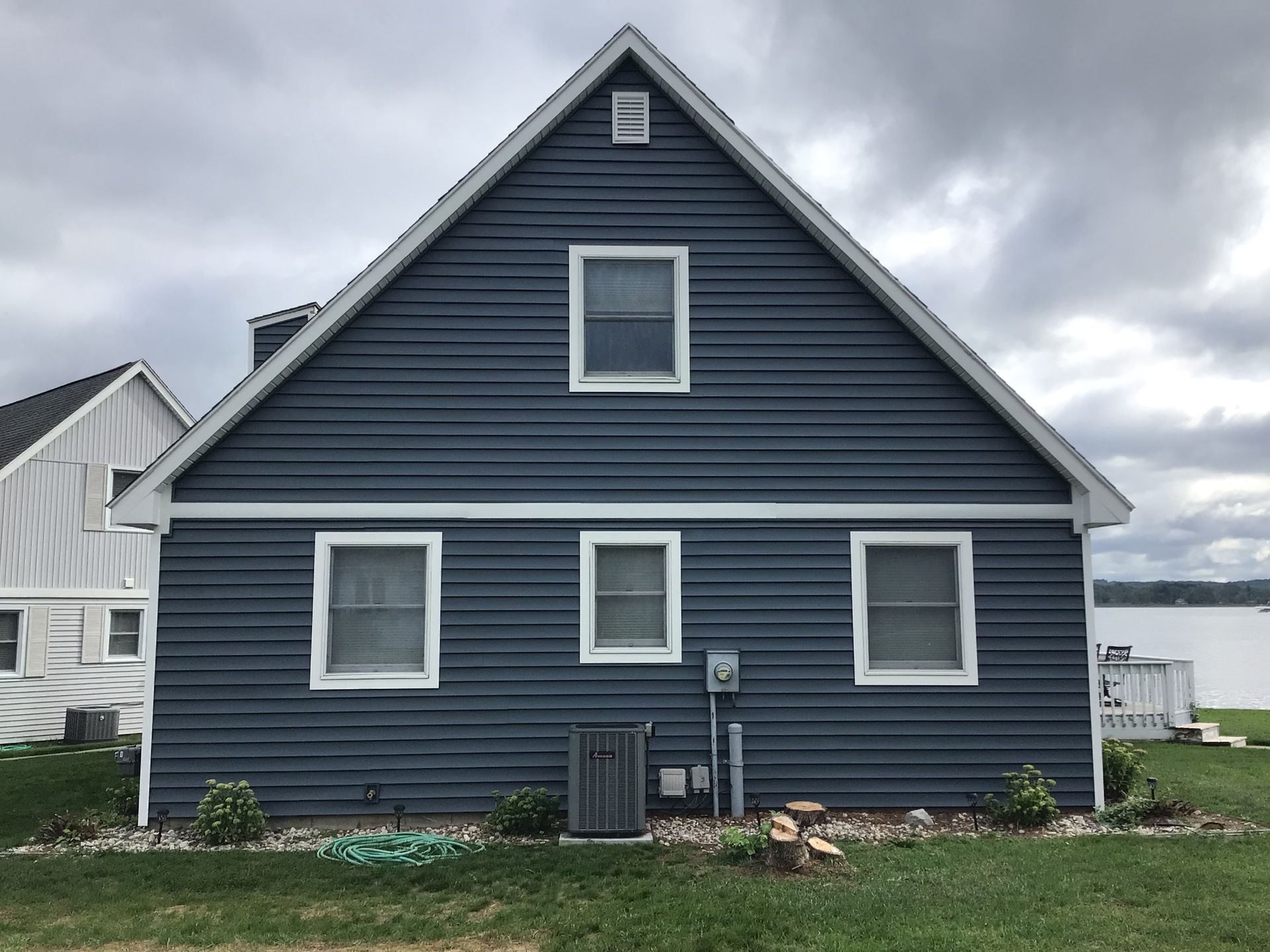 A blue house with white trim and a white roof is sitting on top of a lush green field.