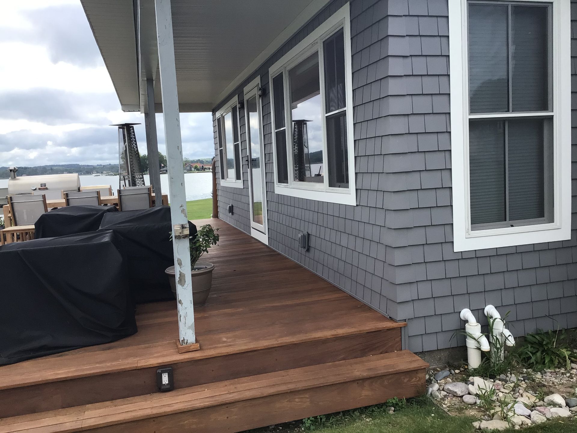 A gray house with a wooden deck and stairs