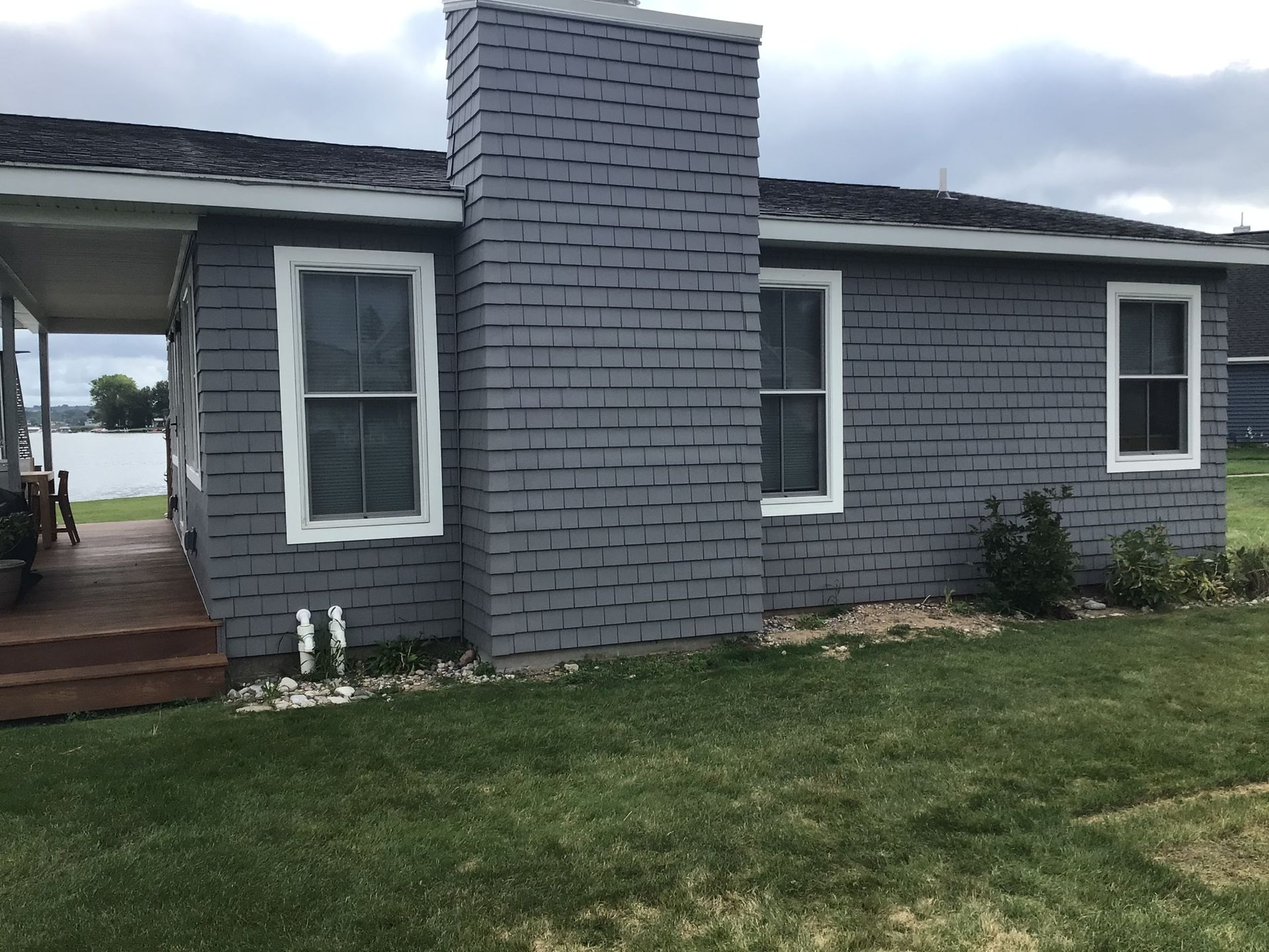 A gray brick house with a porch and a chimney.