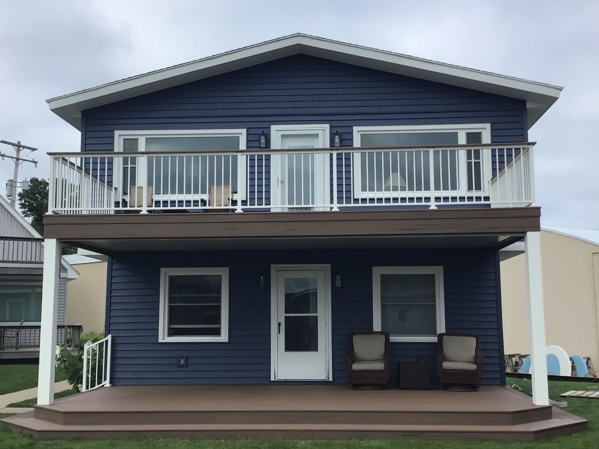 A blue house with a deck and chairs on it
