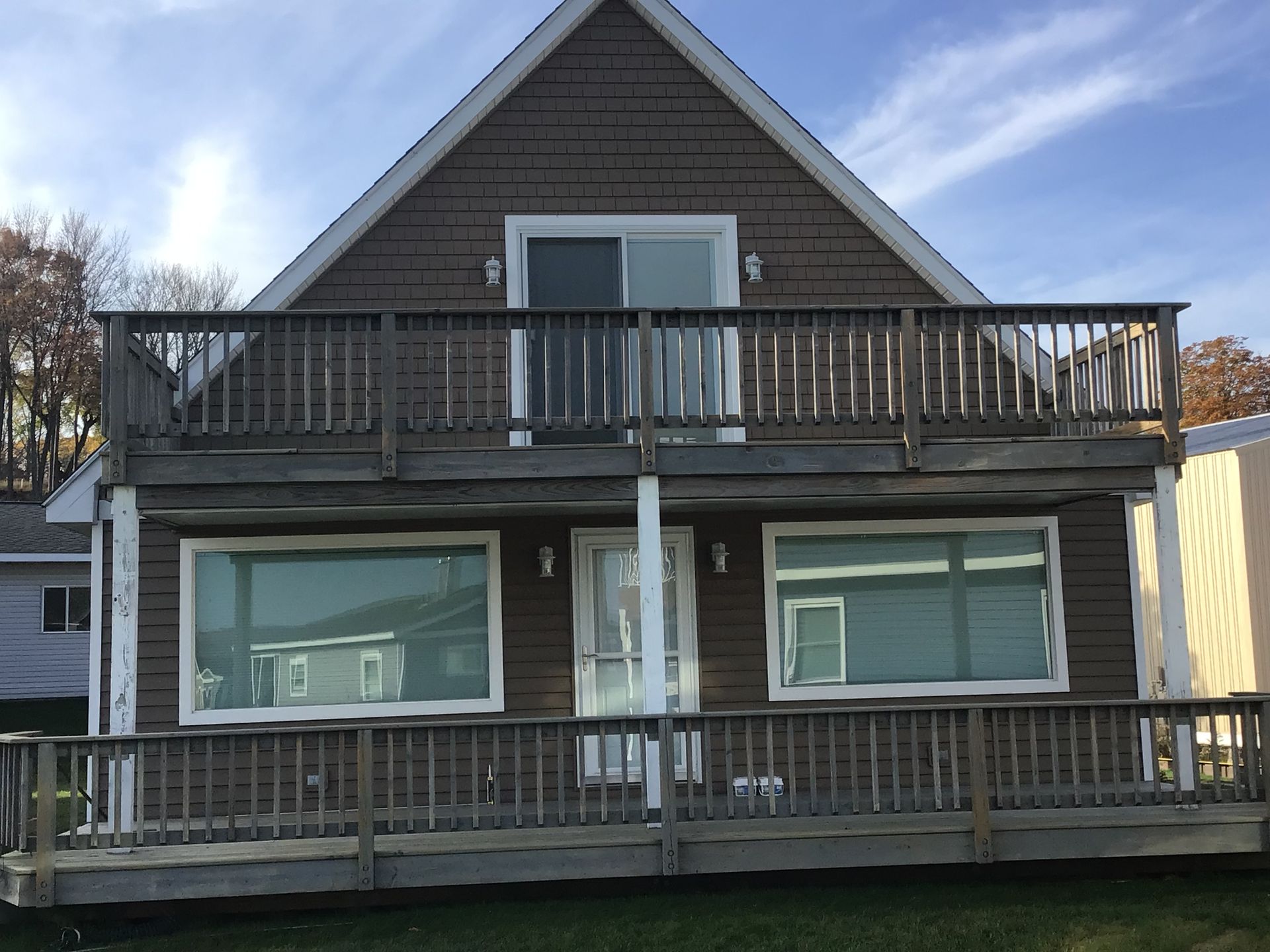 A brown house with a large deck and a blue sky in the background.