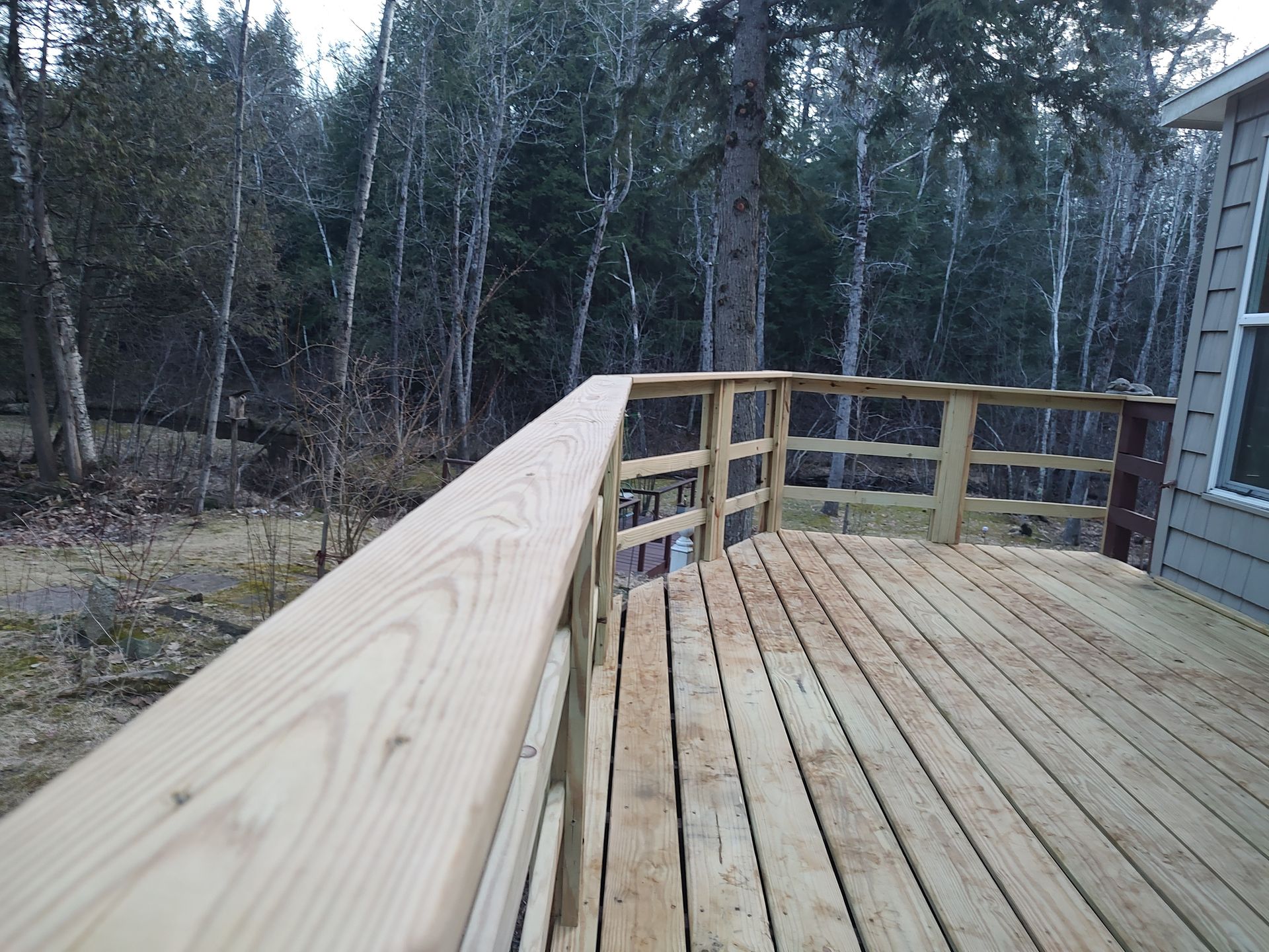 A wooden deck with a railing and trees in the background