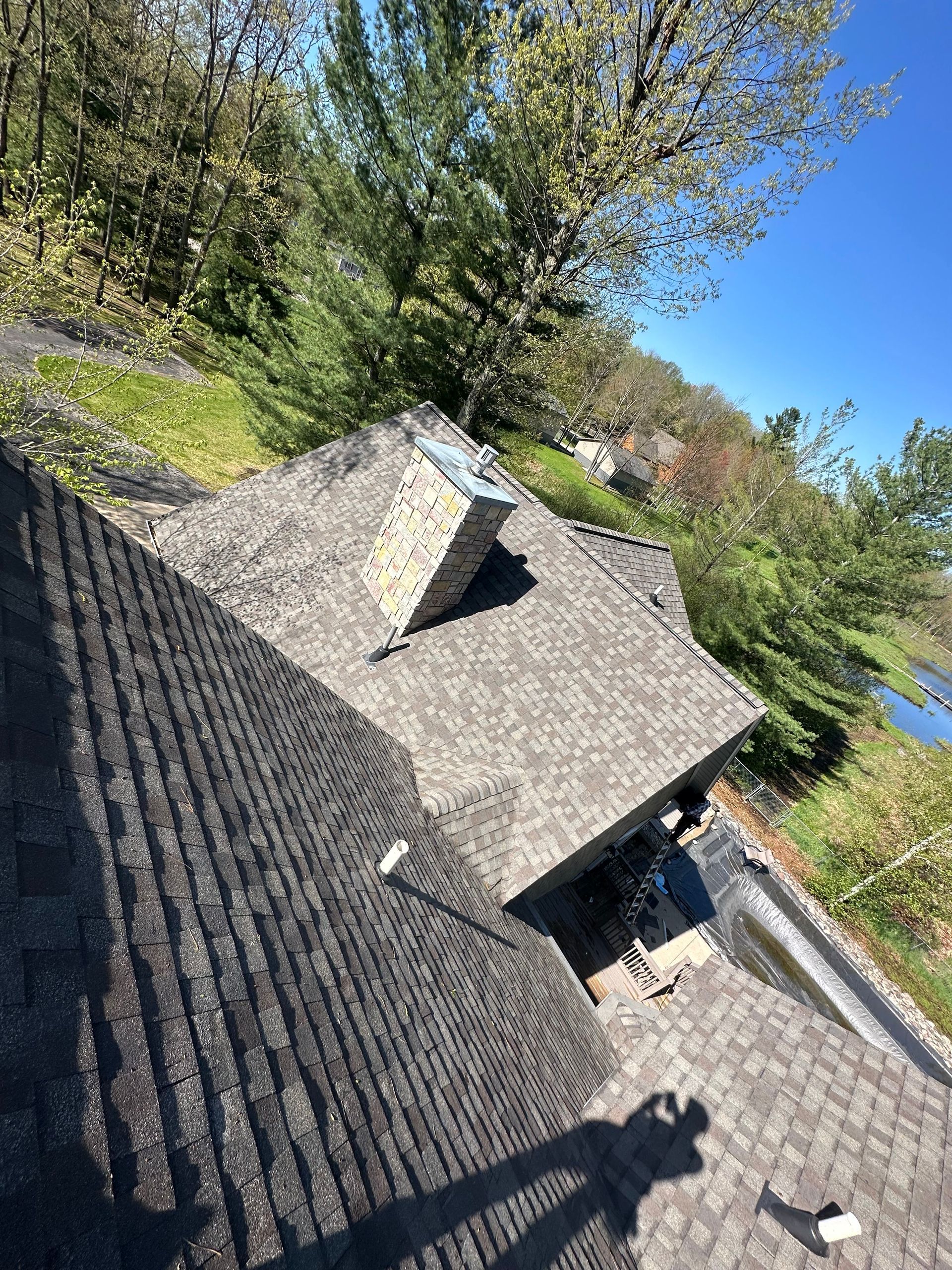 A roof with a chimney on top of it and trees in the background.