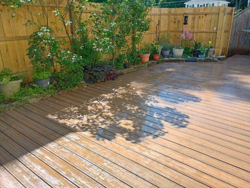 A wooden deck with potted plants and a wooden fence in the background.