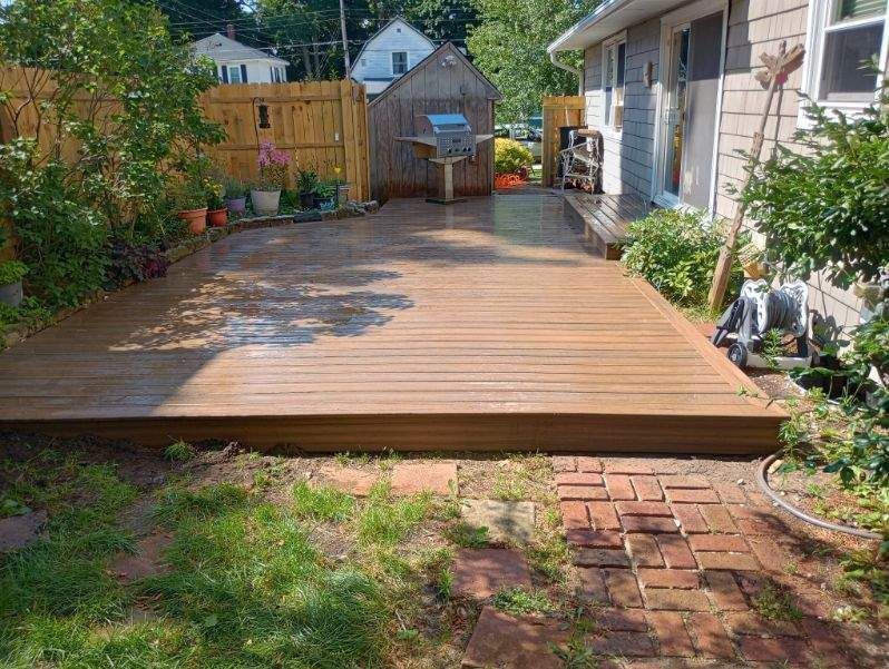 A wooden deck is in the backyard of a house.