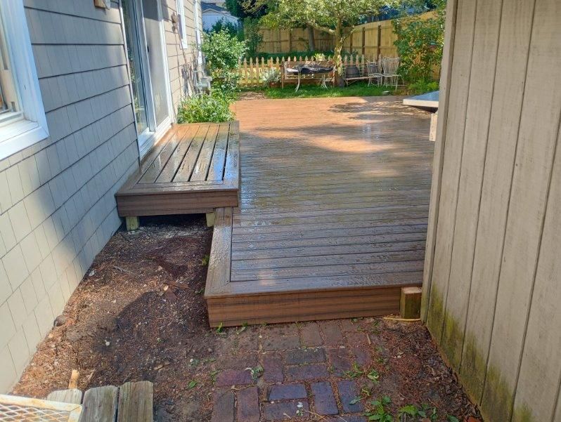 A wooden deck with a brick walkway leading to it
