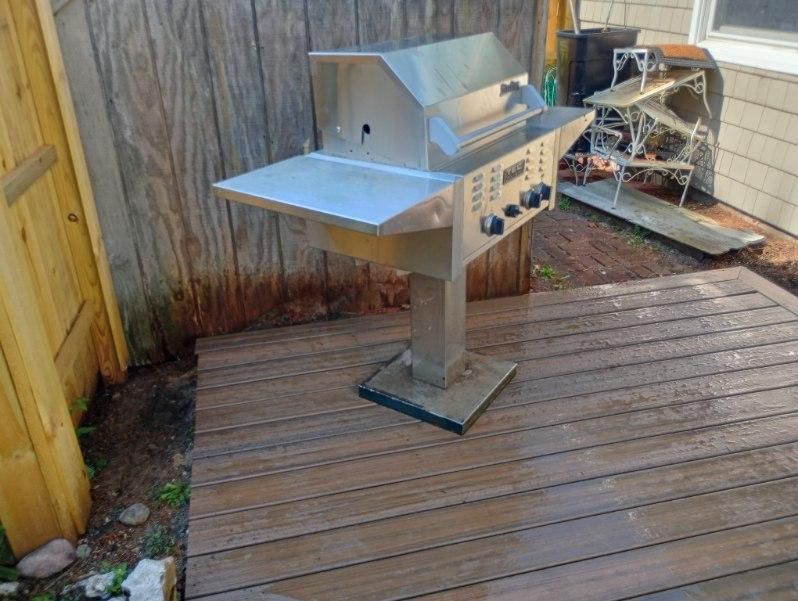 A stainless steel grill is sitting on a wooden deck.
