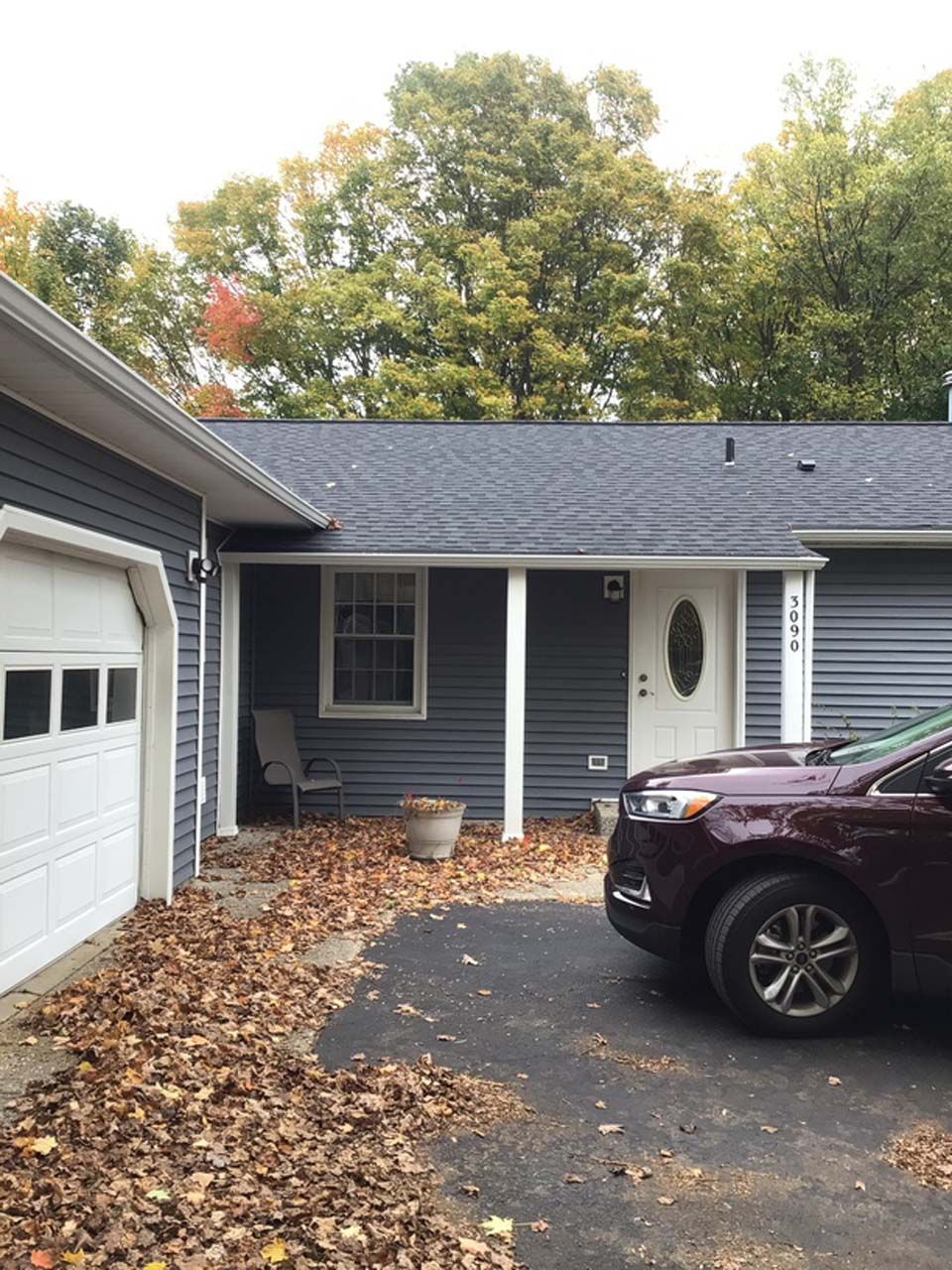 A car is parked in front of a house with a garage.