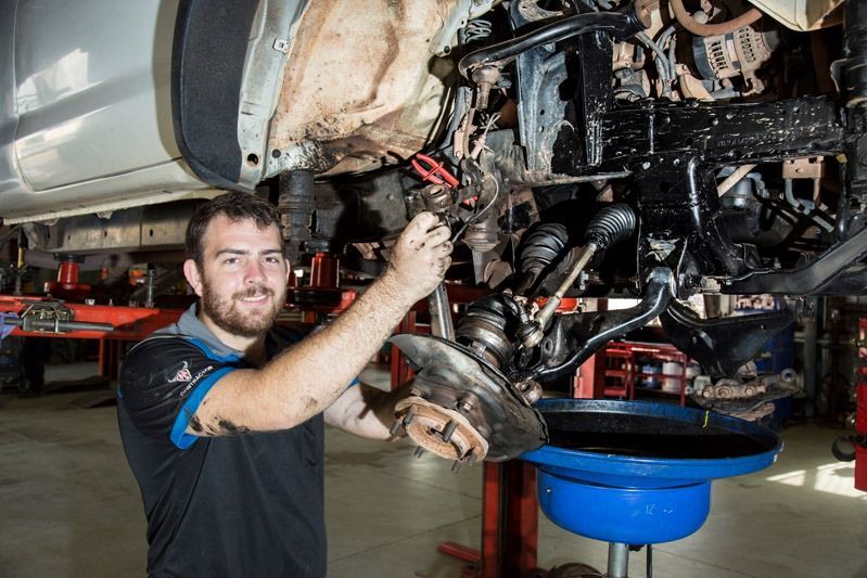 A Mechanic In A Garage Working On The Suspension And Wheel — Auto Inspections & Road Services N.T in Woolner, NT