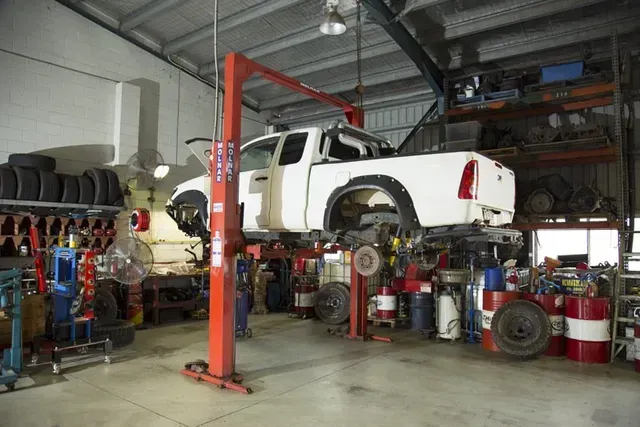 White Pickup Truck Lifted on a Hydraulic Hoist in an Auto Repair Shop — Auto Inspections & Road Services N.T in Woolner, NT