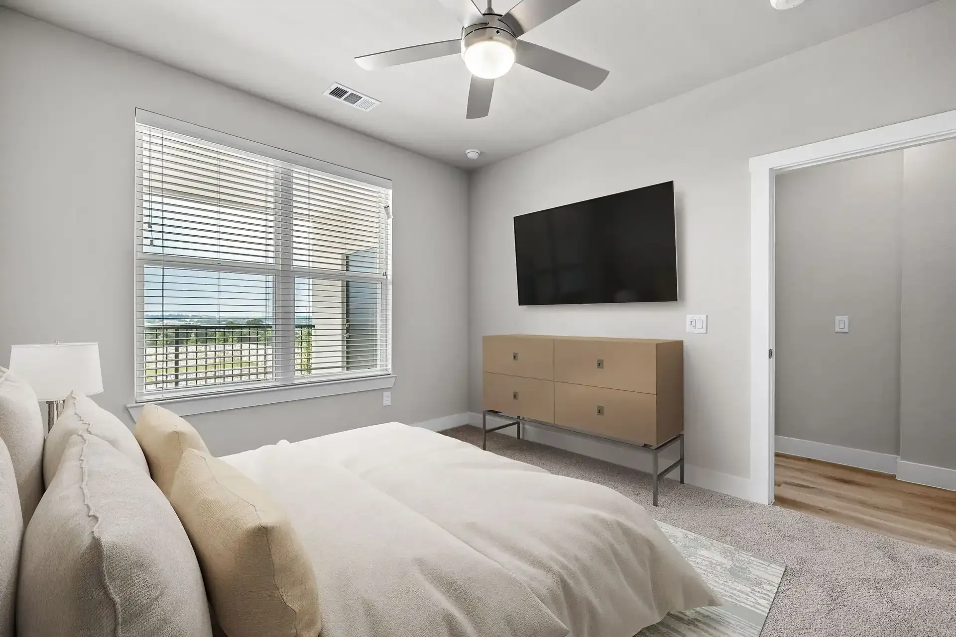 Spacious apartment bedroom with a bed, dresser, television, and ceiling fan at The Gabriel, which offers apartments for rent near Georgetown, TX.