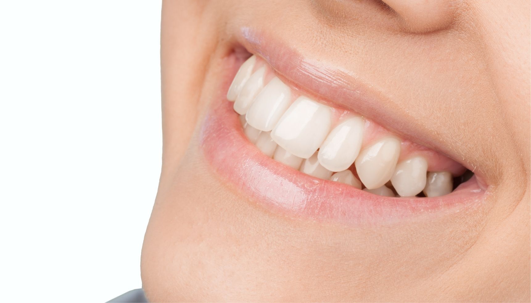 Close-up of a person smiling, showing white, healthy teeth and pink lips.
