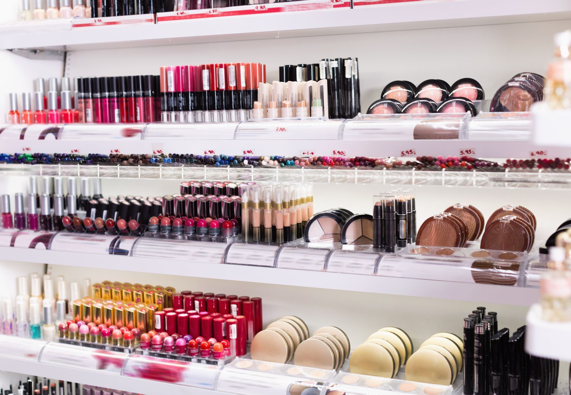 Cosmetics store shelves lined with lipsticks, powders, and makeup compacts