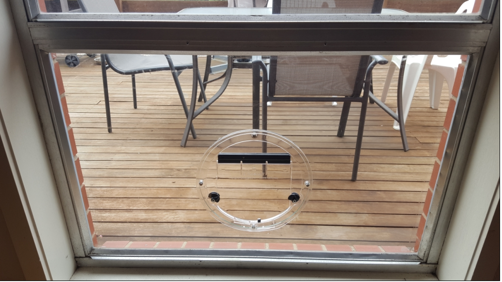 View through a window onto a wooden deck with patio table and chairs