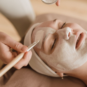 Facial mask being applied with a brush to a reclining person in a spa setting