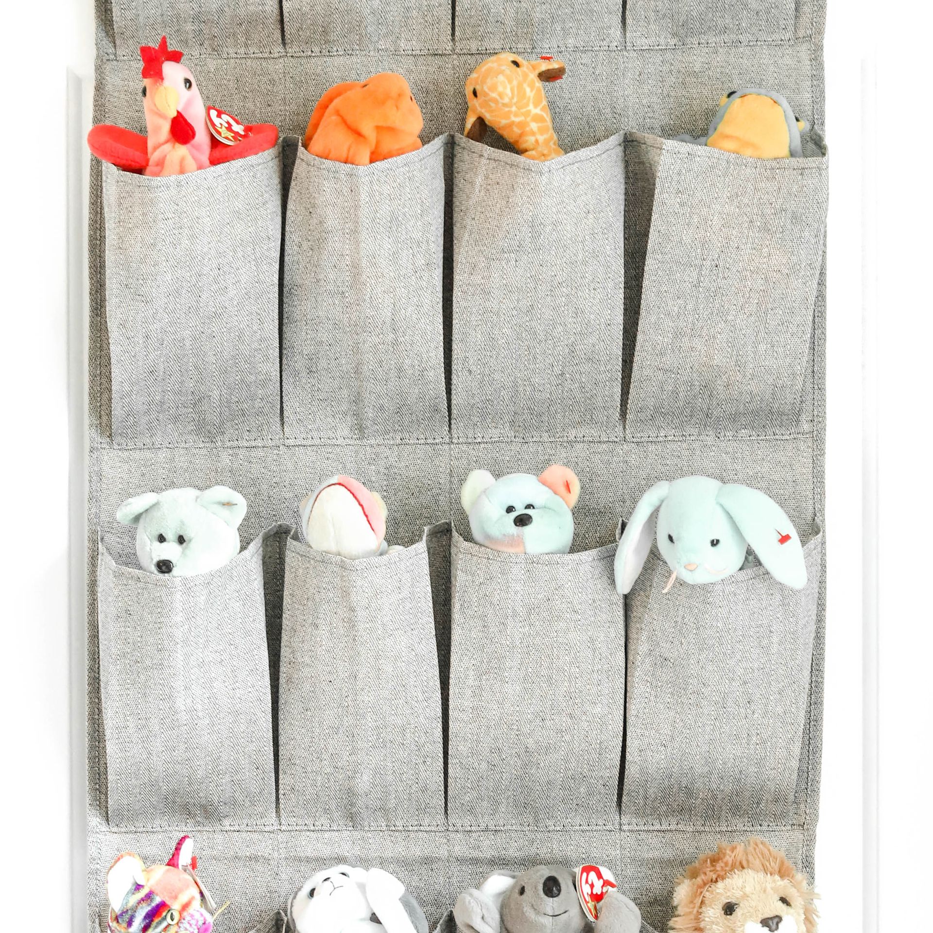 A wall hanging organizer filled with stuffed animals on a white background.
