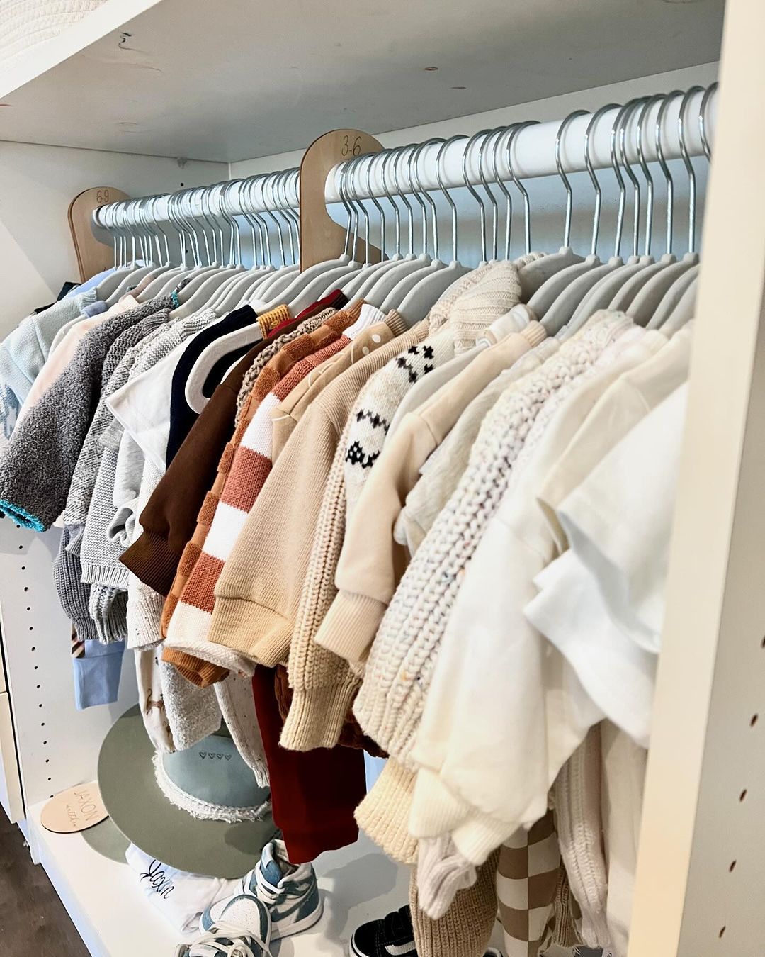 A closet filled with lots of baby clothes hanging on racks.
