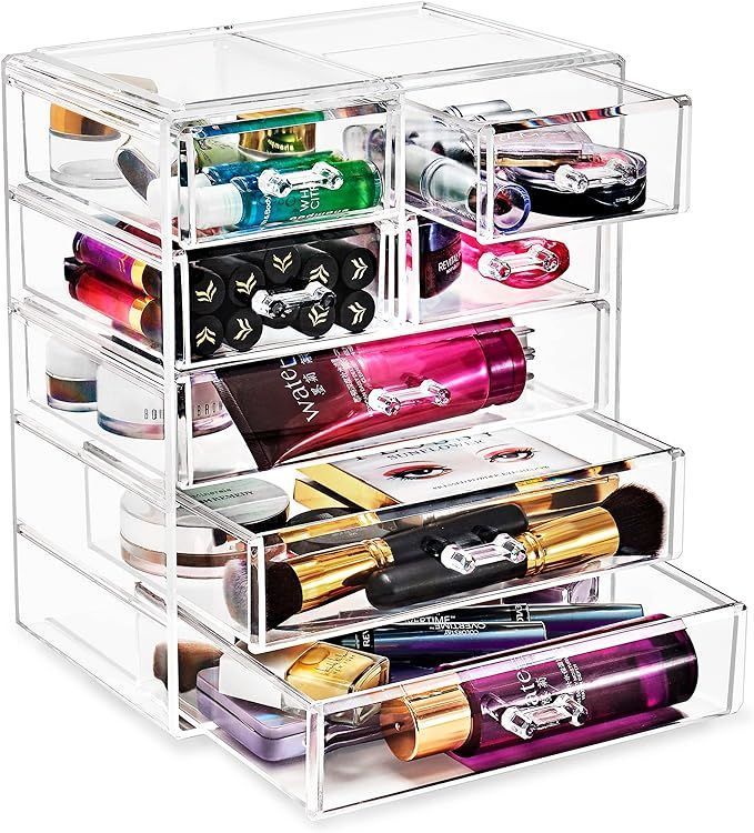 A clear acrylic cosmetic organizer with drawers filled with cosmetics.