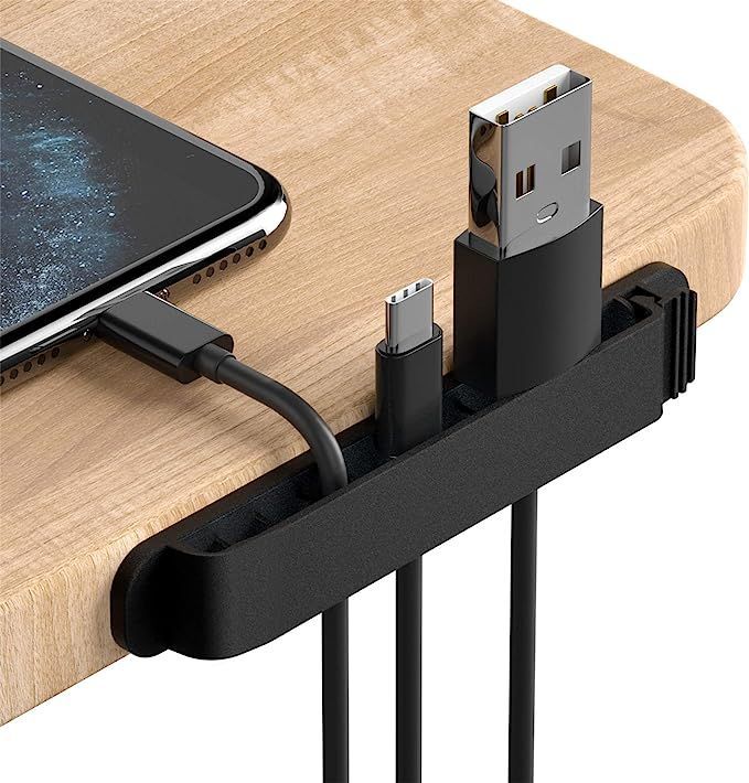 A phone is plugged into a cord holder on a wooden table.