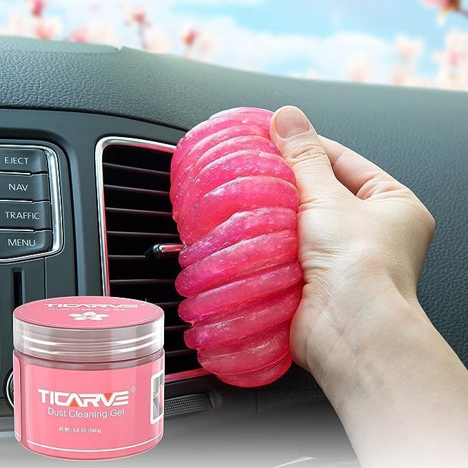 A person is holding a pink object in front of a car air vent.