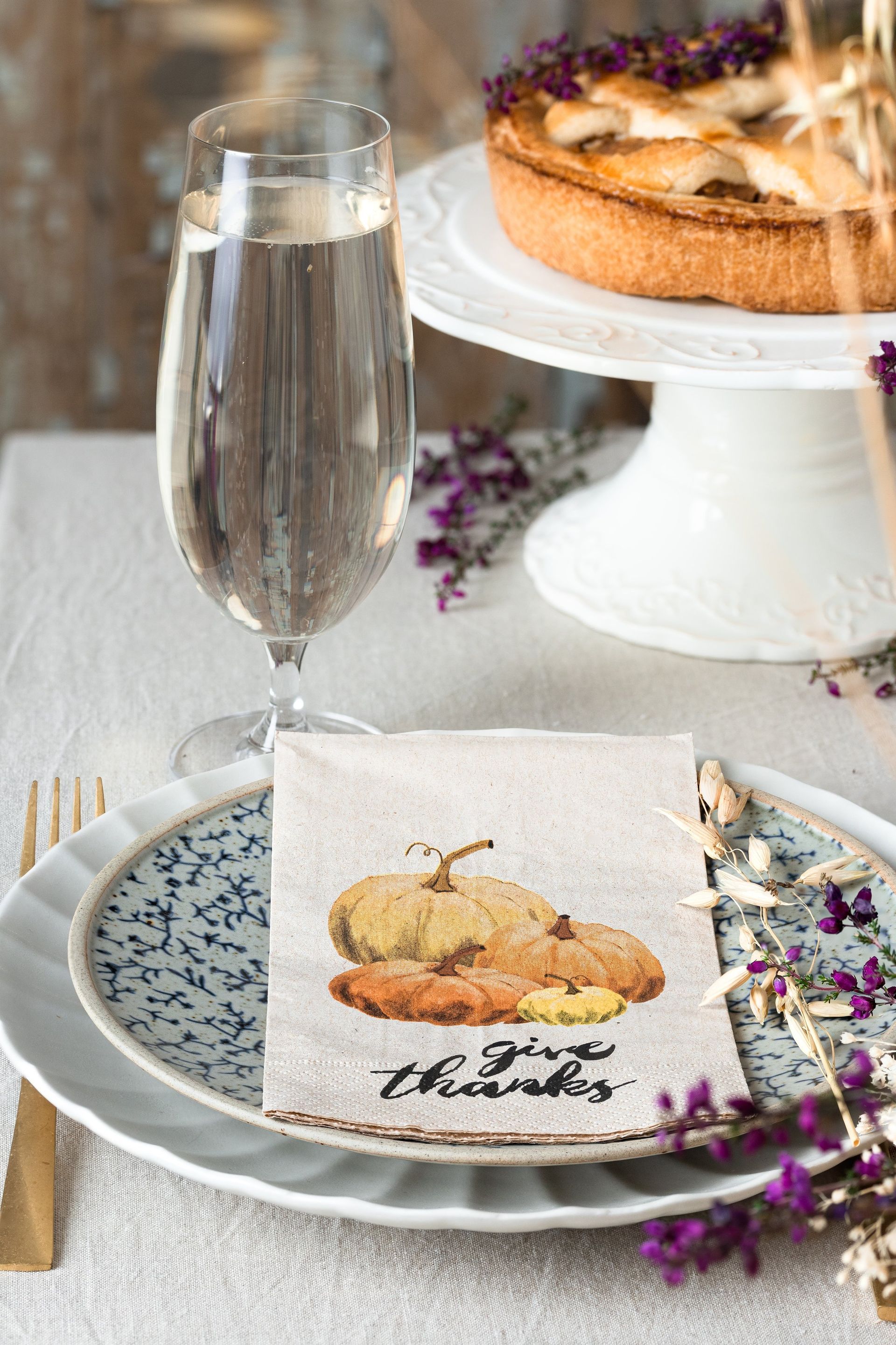 A table setting for thanksgiving with plates , a napkin , a glass of wine , and a pie.