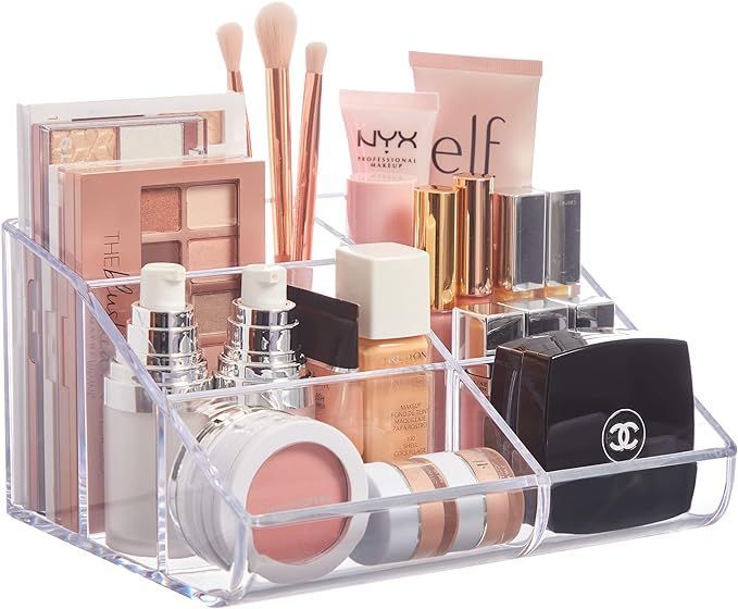 A clear acrylic makeup organizer filled with various makeup products.