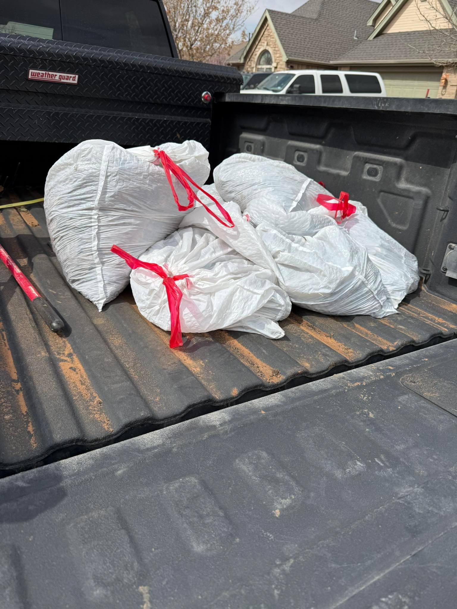 Three white trash bags tied with red ties in a pickup truck bed