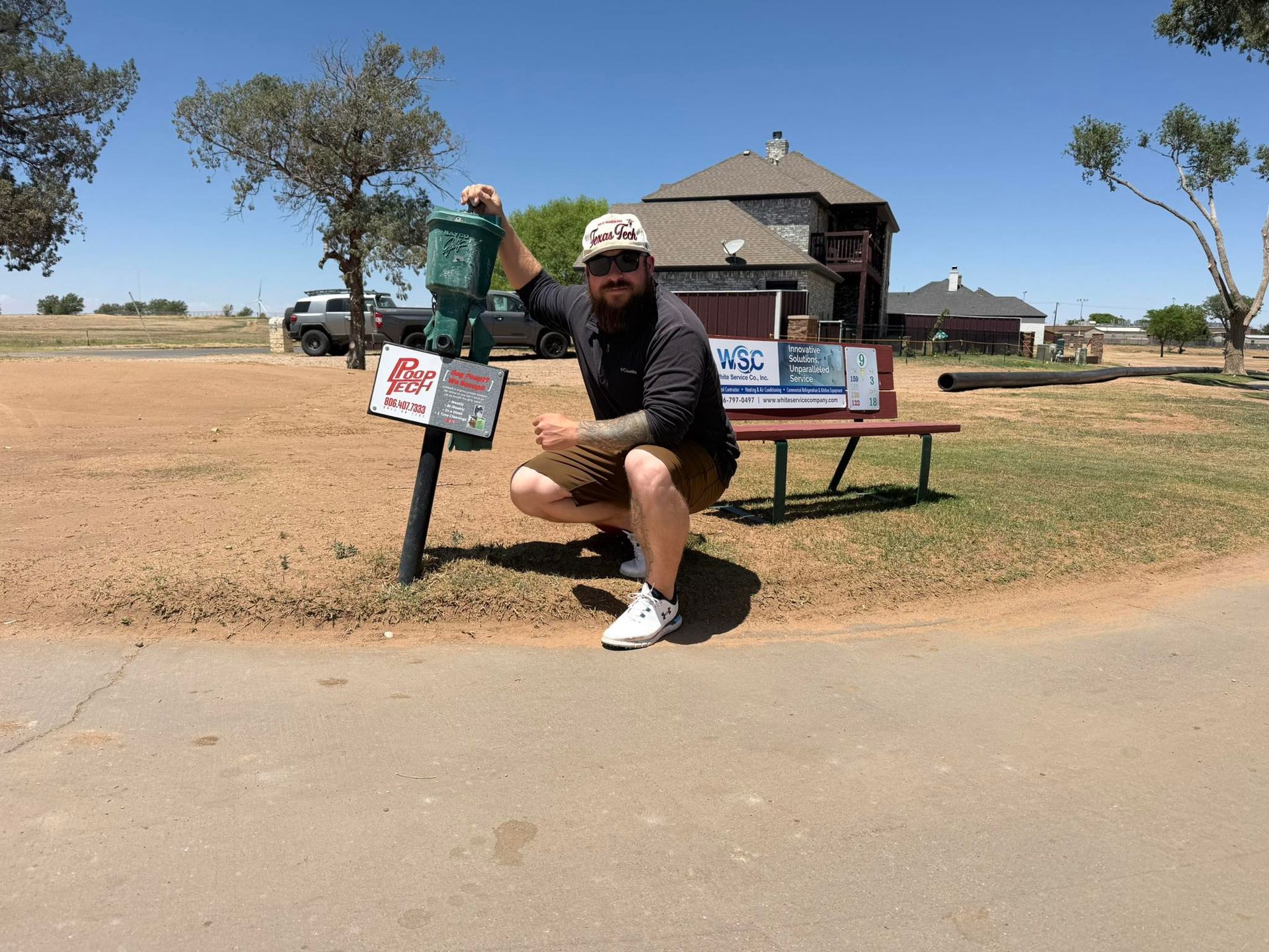 Person posing on a lawn with signs in front of a rustic house on a sunny day